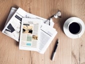 Newspaper with tablet on wooden table