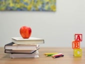 A school desk with ABC blocks, books, and an apple.